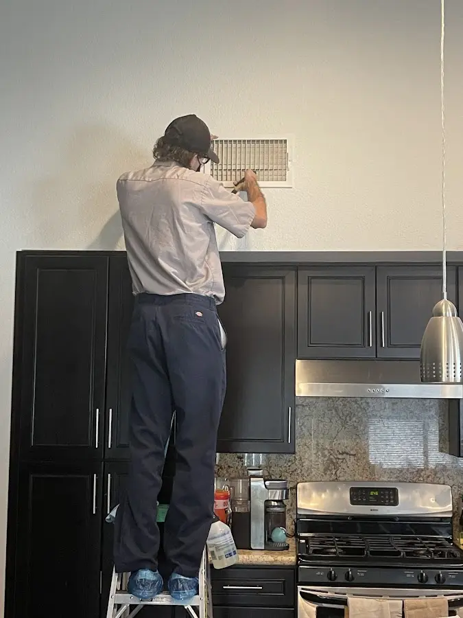 Technician inspecting an air vent during HVAC service in Penitas